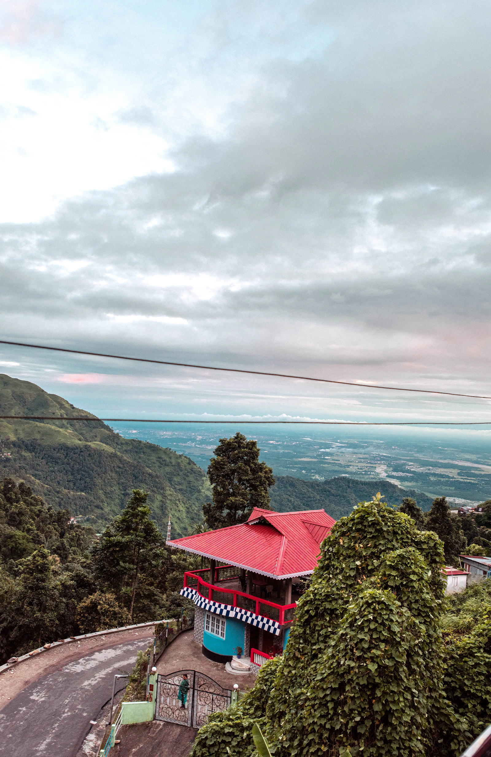 A red roofed building perched above a bend of the hill road on the drive up to Darjeeling, the plains lost in haze below