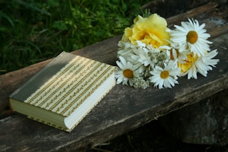 white and yellow flowers beside closed book