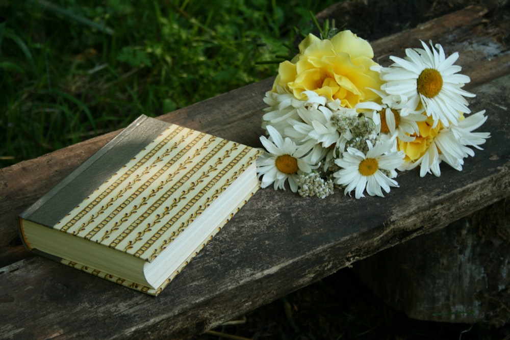 white and yellow flowers beside closed book