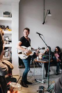 man with guitar near people inside room