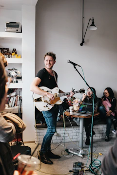 man with guitar near people inside room