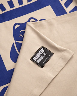 A fabric featuring a blue stylized cat design on a beige background, along with a sewn label that reads 'KIKI OSAKA' in both English and Japanese characters.