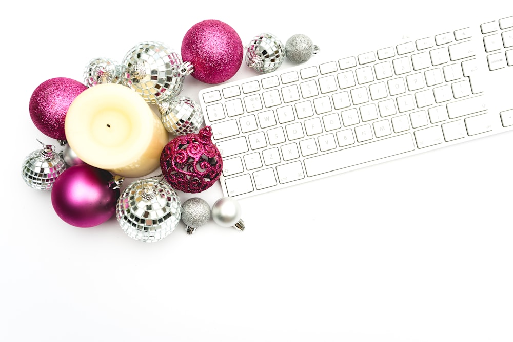 Apple Magic Keyboard beside pink and silver baubles and candle