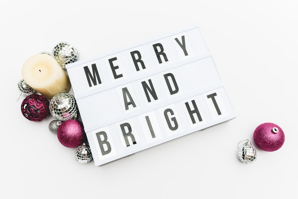 Merry and Bright print board beside silver and pink baubles and candle