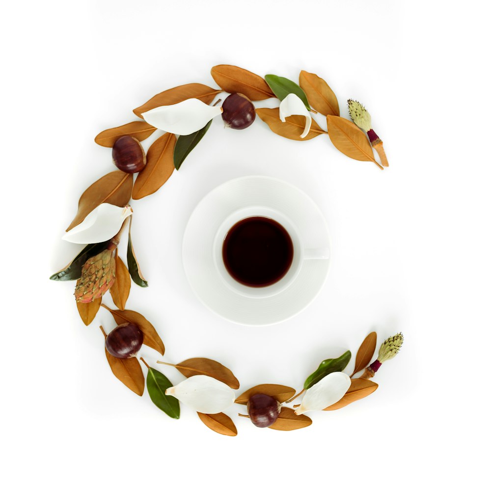 white teacup filled with red liquid surrounded with chestnut