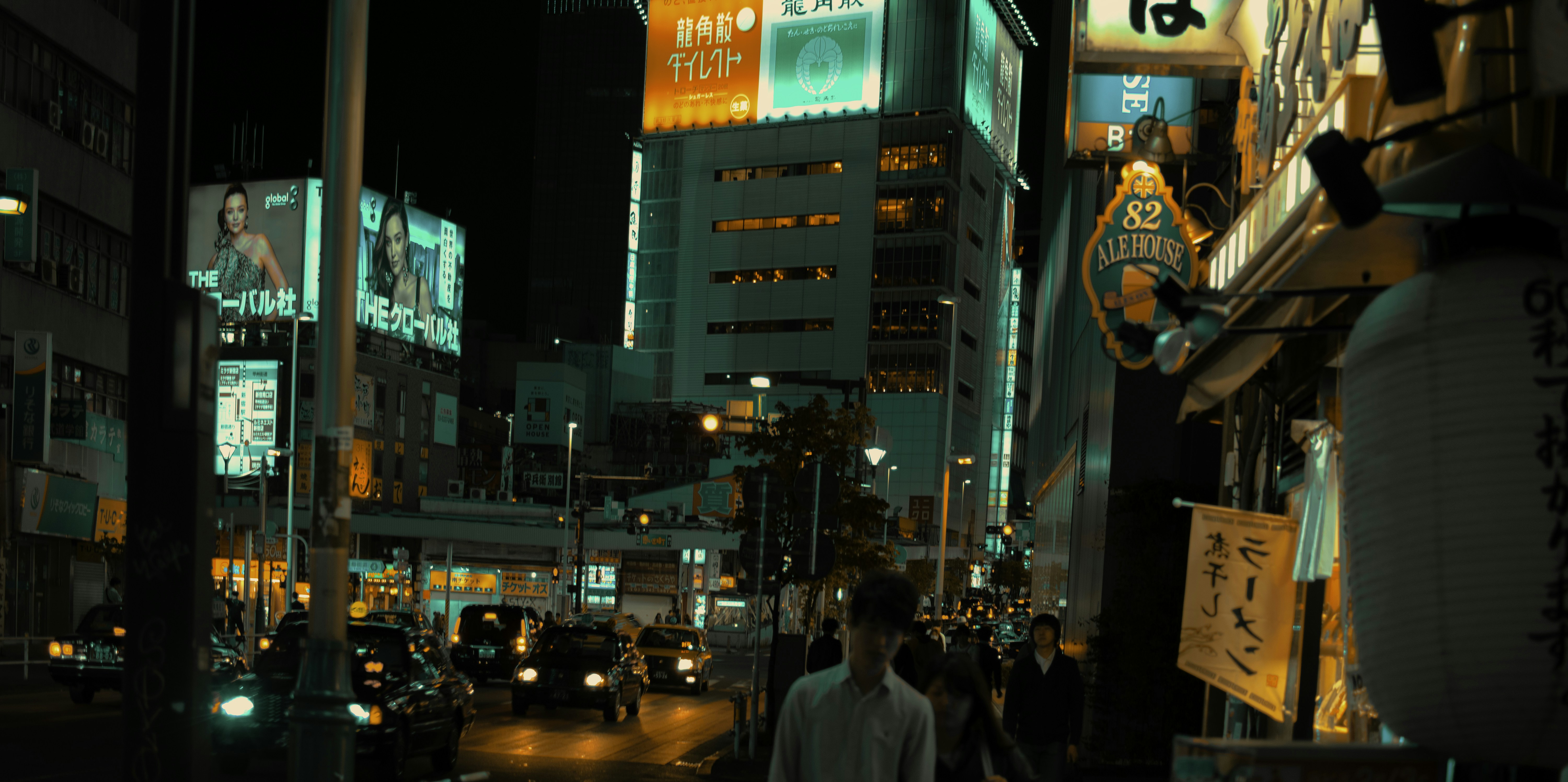 Busy Tokyo street at night, neon lights, train station entrance in background