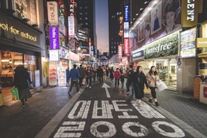 Brightly lit storefronts of popular retail brands at St James Shopping in the evening.