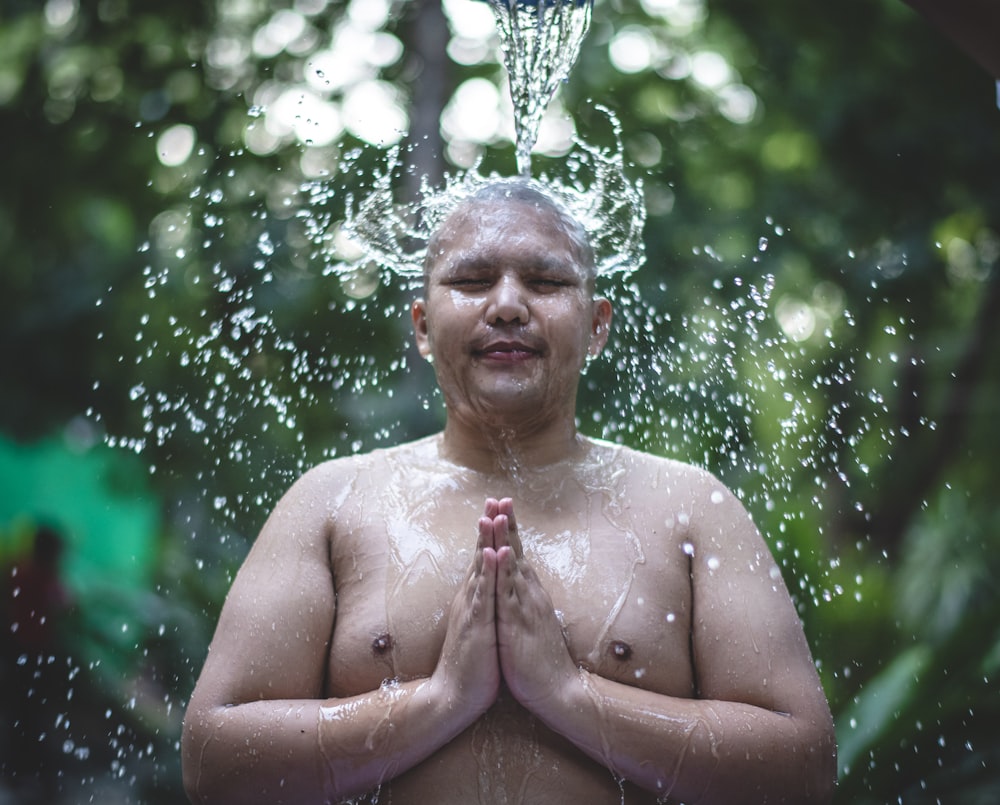 time-lapse photography of water pouring over a naked man