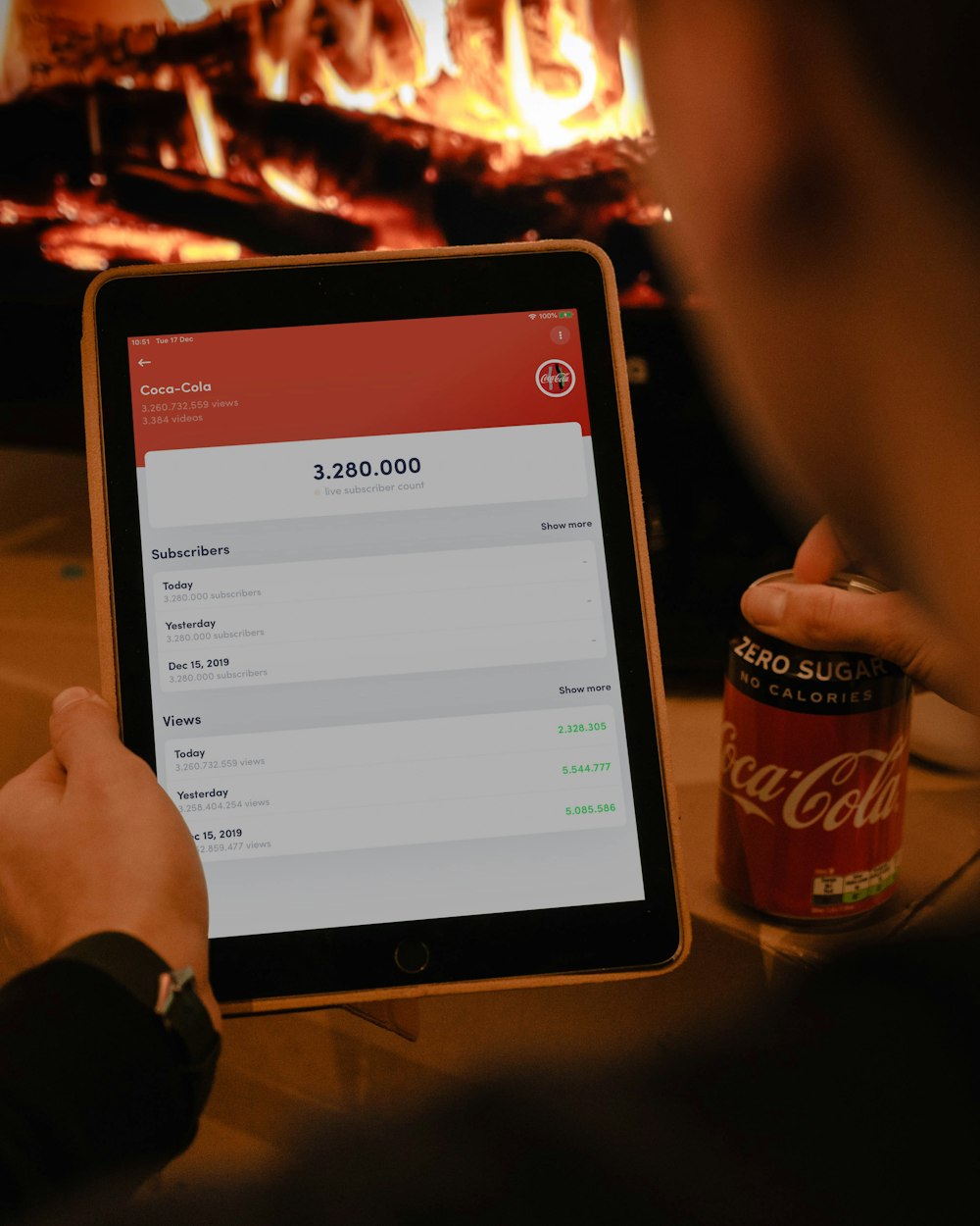person using iPad while holding Coca-Cola soda can