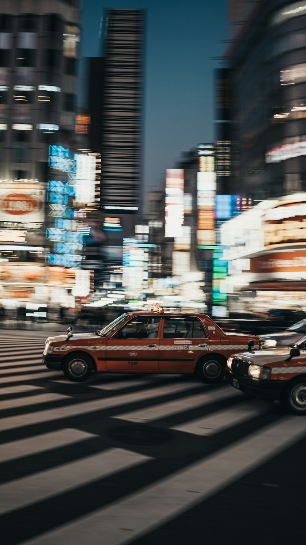 selective focus photography of vehicles passing buildings at night