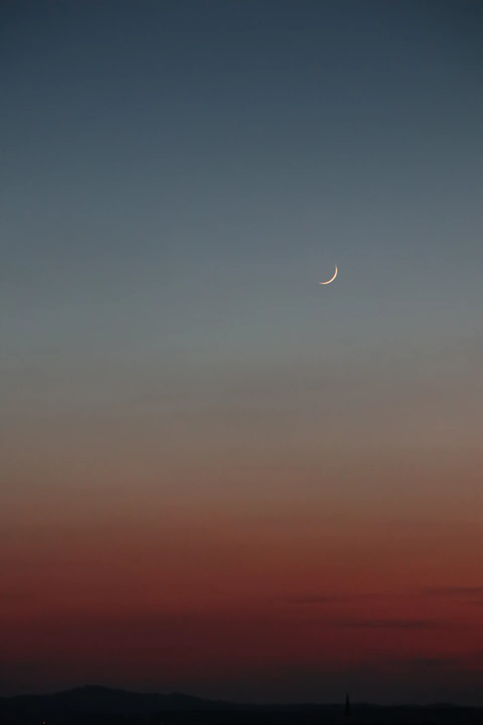 Serene night sky with crescent moon partially obscured by clouds in rising position
