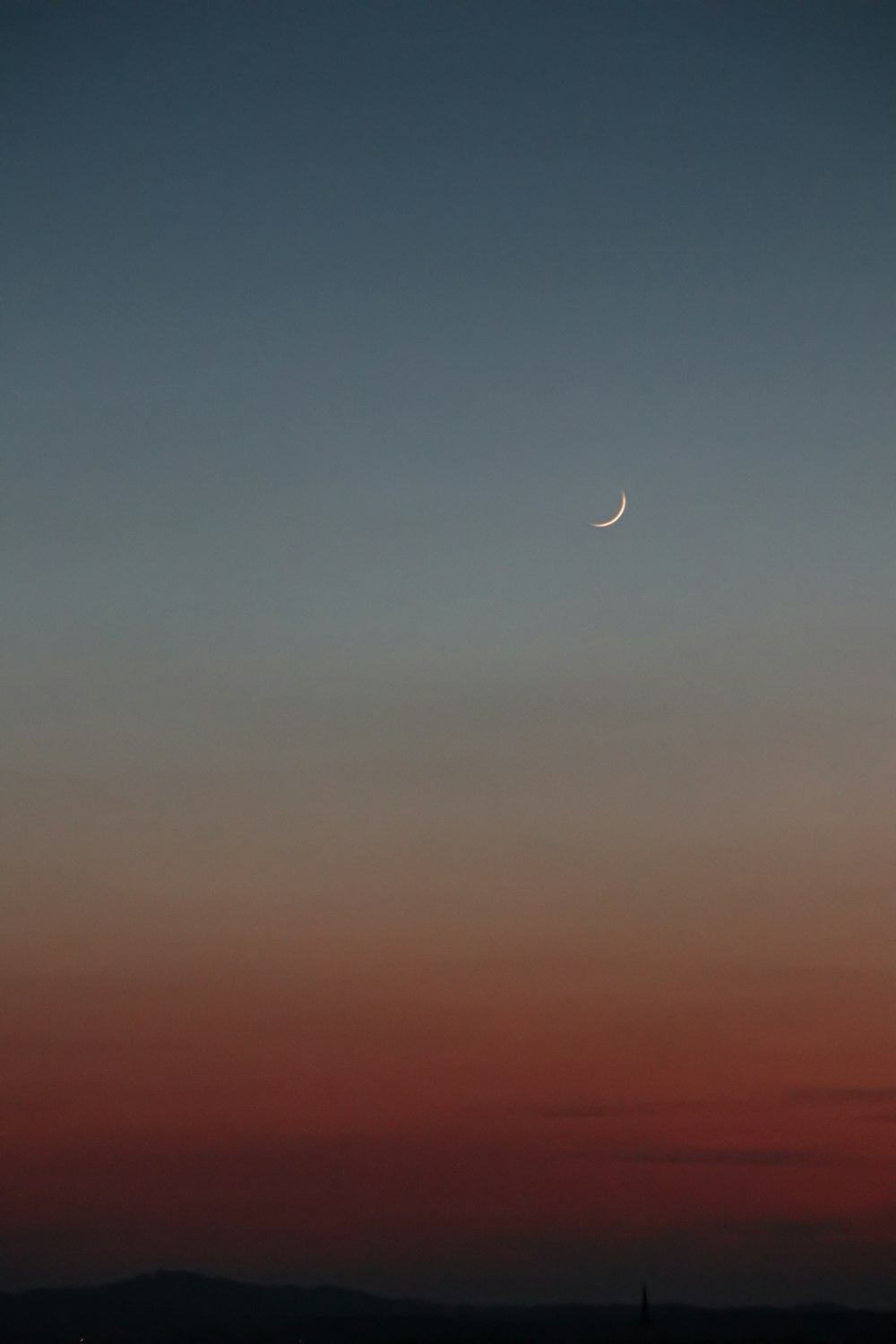 the moon is seen in the sky over a city