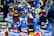 A vibrant display of sports merchandise with various hats, caps, and flags in blue and yellow, prominently featuring the Bosnia and Herzegovina flag and football-related items. There are shirts and scarves with team logos, including a jersey with the name Mbappe and the number 29.