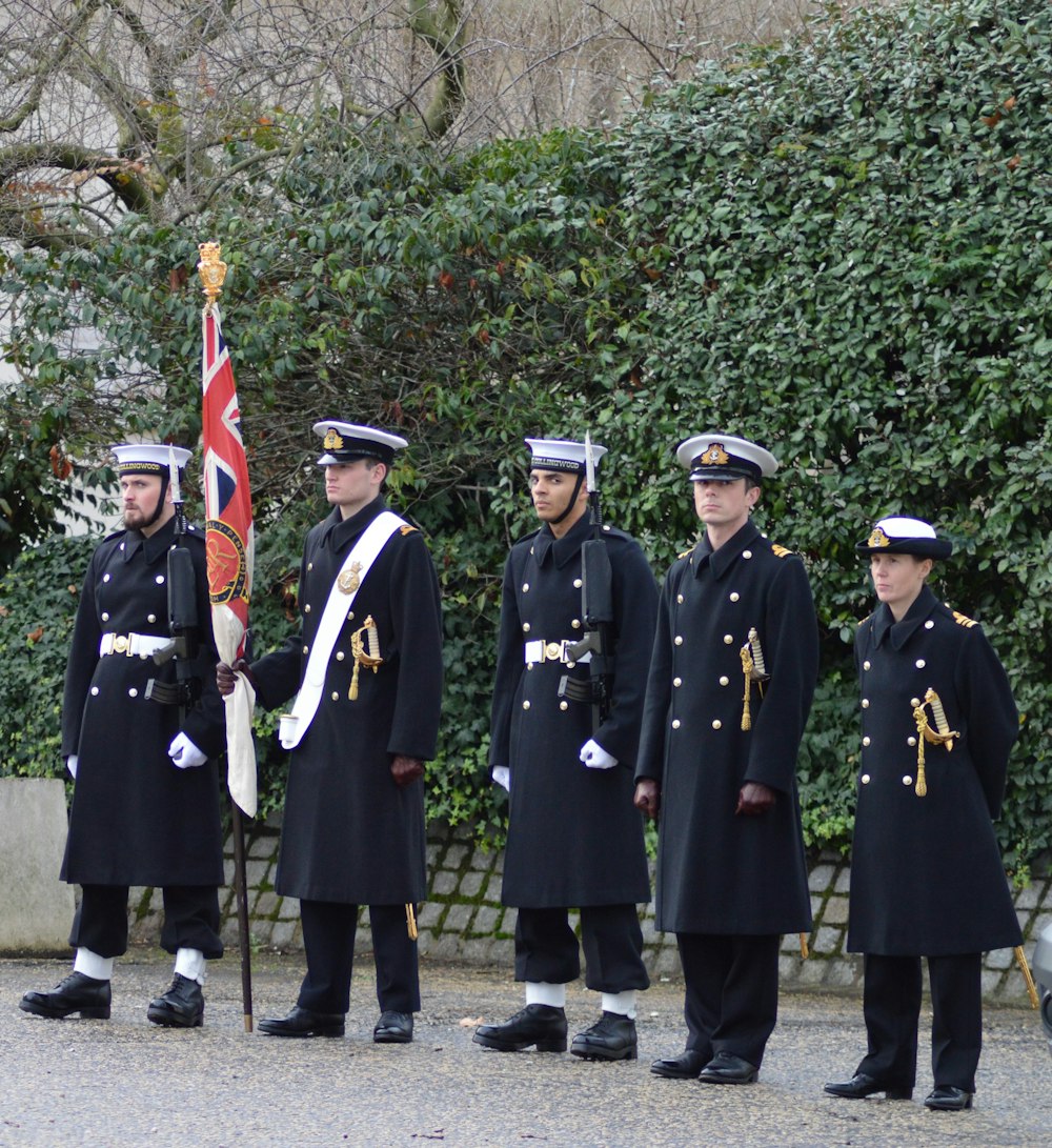 five men wearing soldier coats during daytime