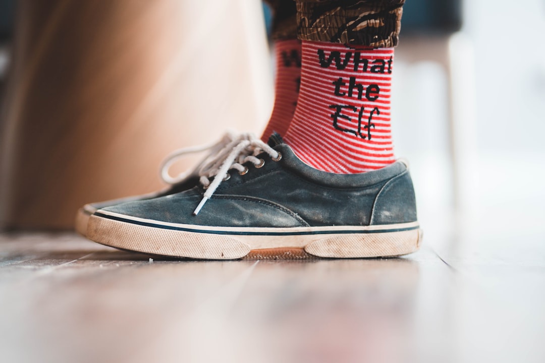 selective focus photography of person wearing What the Elf socks and gray sneakers