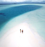 Couple enjoying a private beach with crystal-clear waves and white sand.