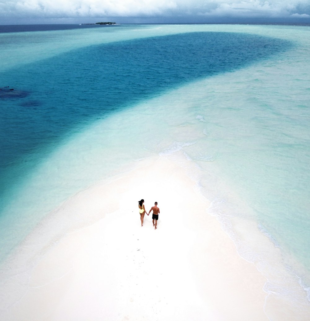 deux personnes marchant sur un banc de sable