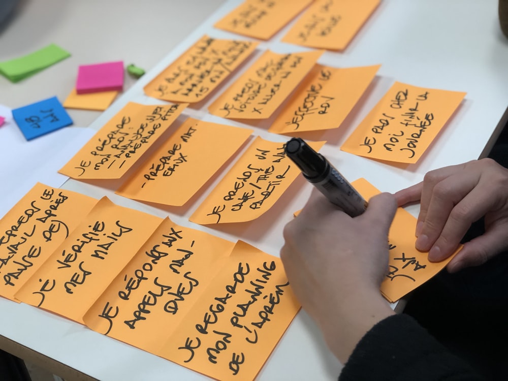 shallow focus photo of person writing on orange paper sheet