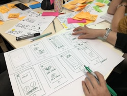 person writing on printing paper for designing web pages