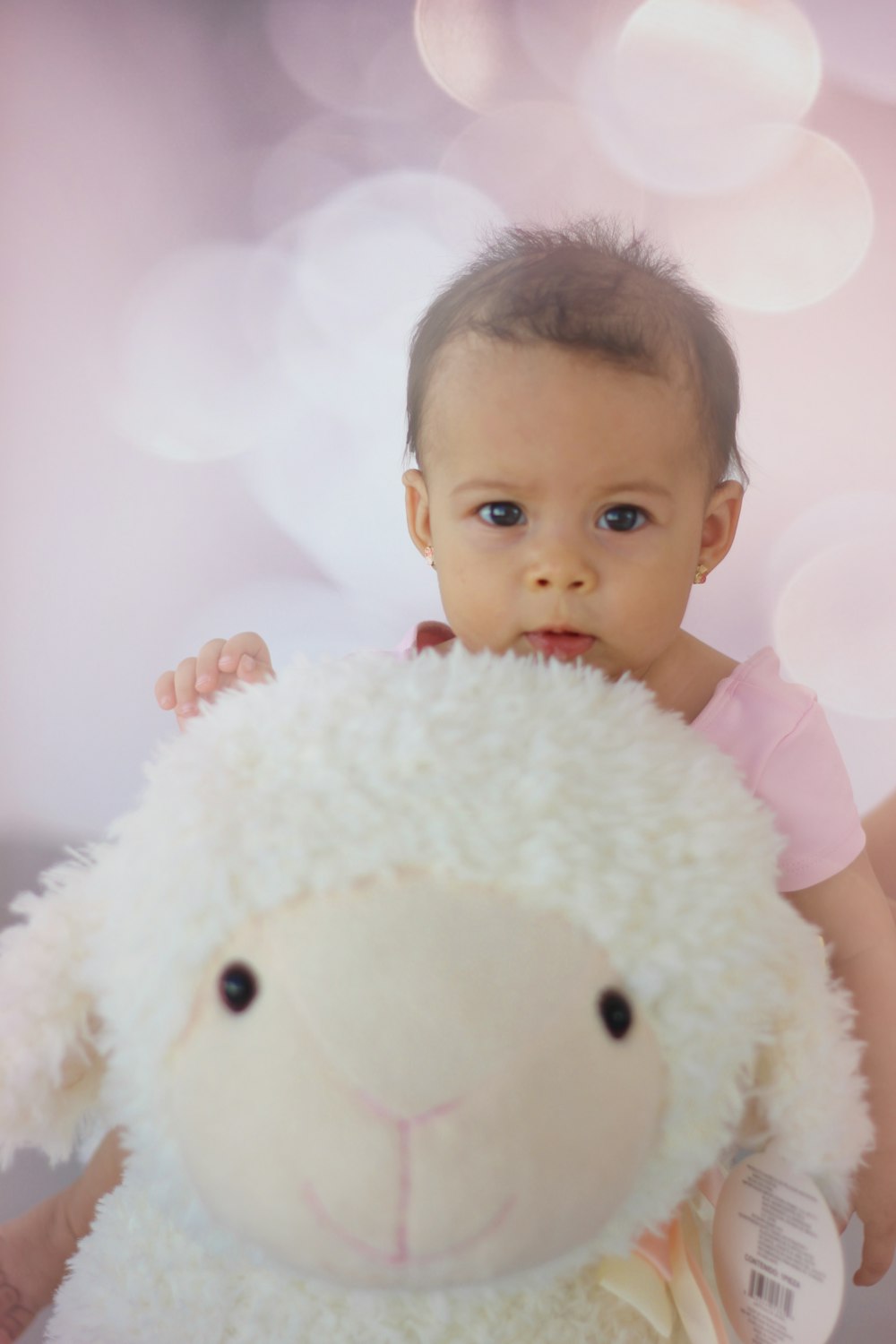 selective focus photography of girl holding sheep plush toy