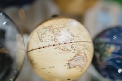 A close-up of a globe features detailed geographical markings, prominently displaying parts of Southeast Asia and the Indian Ocean. The globe's surface has a muted, vintage tone, and the background is softly blurred, highlighting the globe.