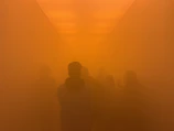 A high-end commercial lobby engulfed in thick yellow-hued fog as intruders are disoriented.
