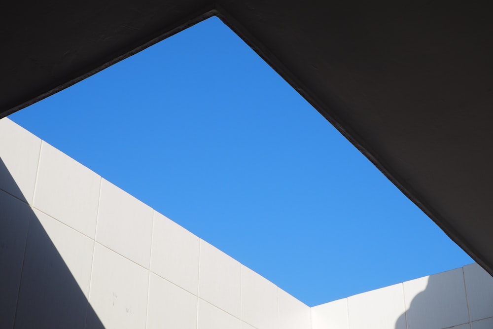 low-angle photography of a white concrete building under a calm blue sky