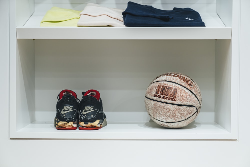 Foto mit flachem Fokus von einem Paar schwarzer Nike-Turnschuhe neben braunem Basketball