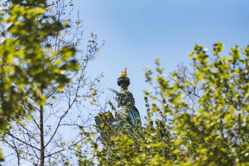 a statue on top of a building surrounded by trees