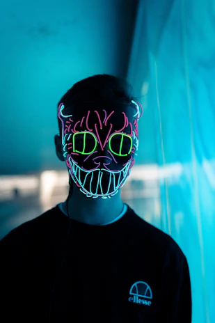 Close-up of a custom t-shirt featuring a glowing demon mask design with neon accents on a black fabric.