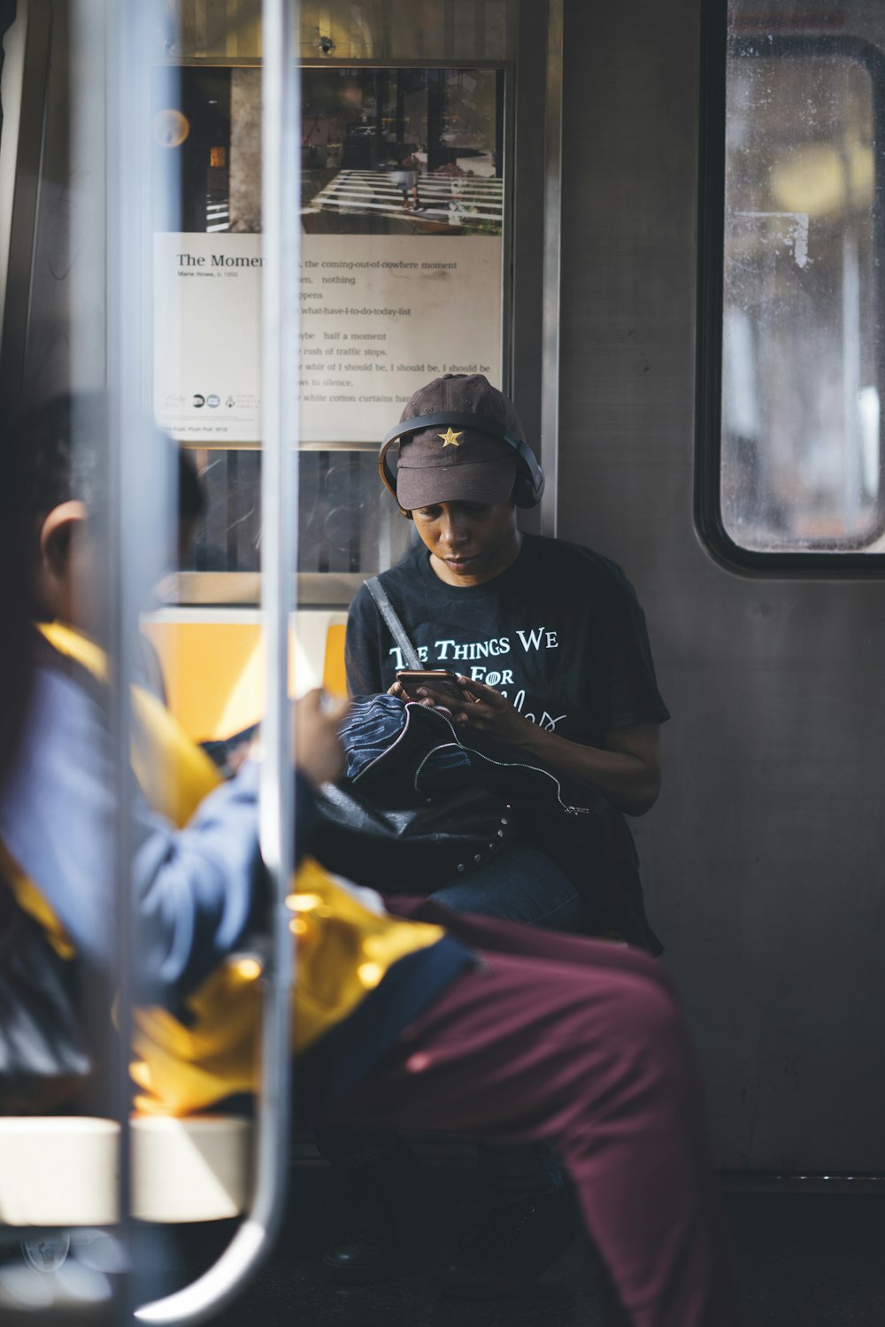 man using phone while sitting near another person