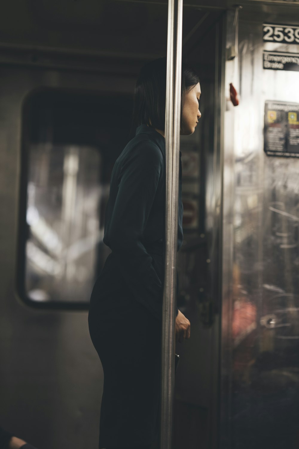 woman wearing black long-sleeved blouse standing near metal post inside train
