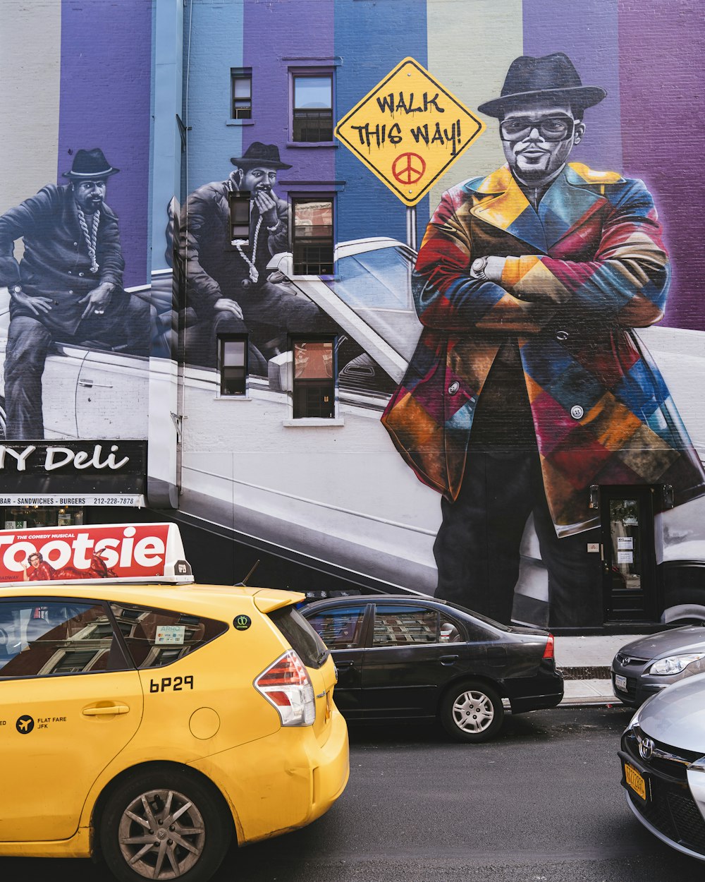 different vehicles on road near wall with multicolored art