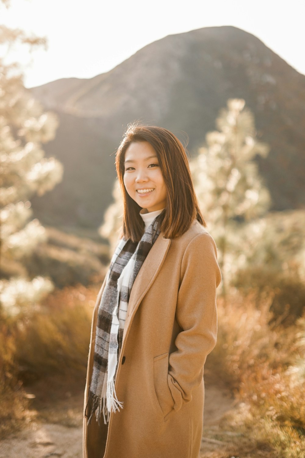 smiling and standing woman wearing brown coat