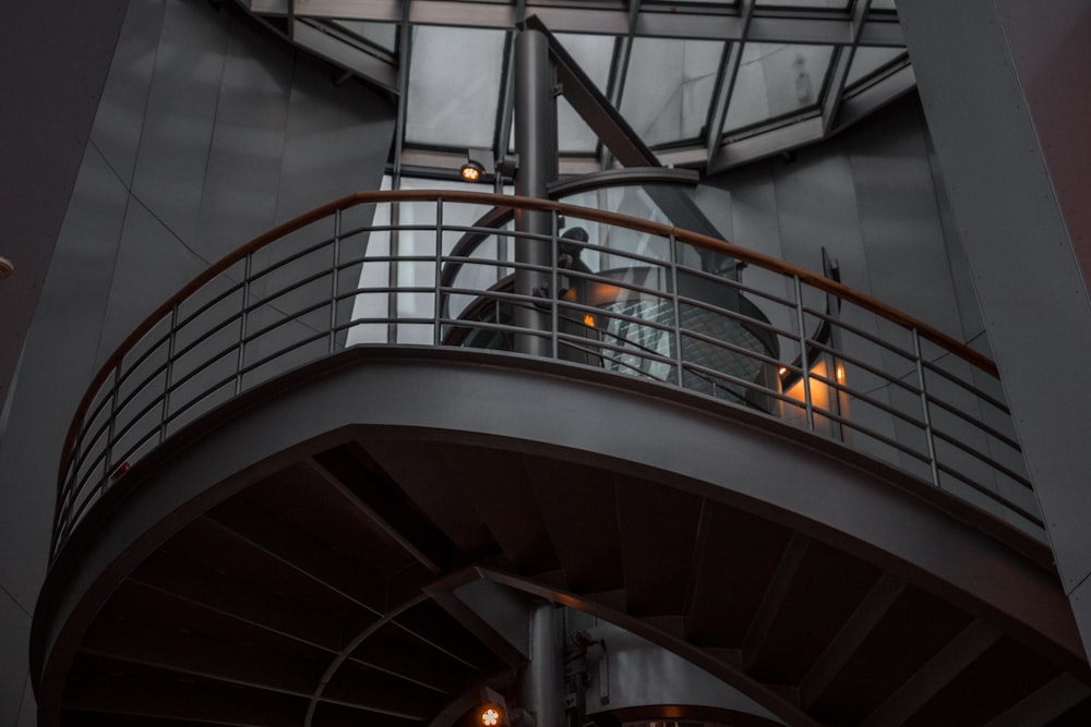 a man standing on a balcony next to a spiral staircase