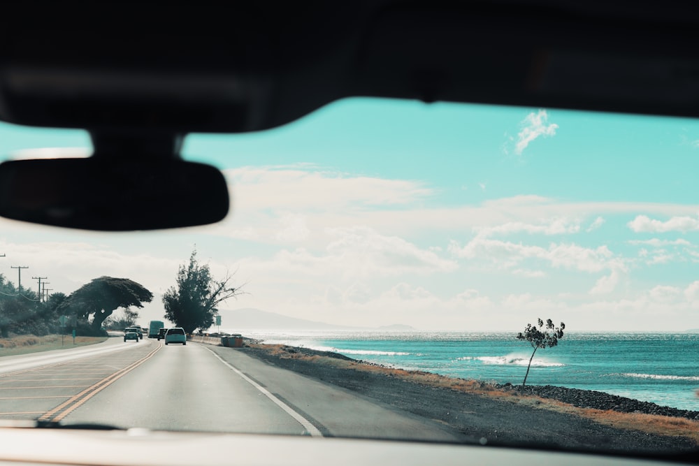 different vehicles on road viewing blue sea under white and blue sky