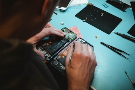 person repairing smartphones under a lighted table