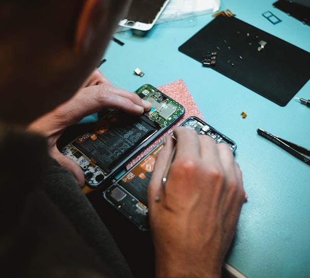 person repairing smartphones under a lighted table