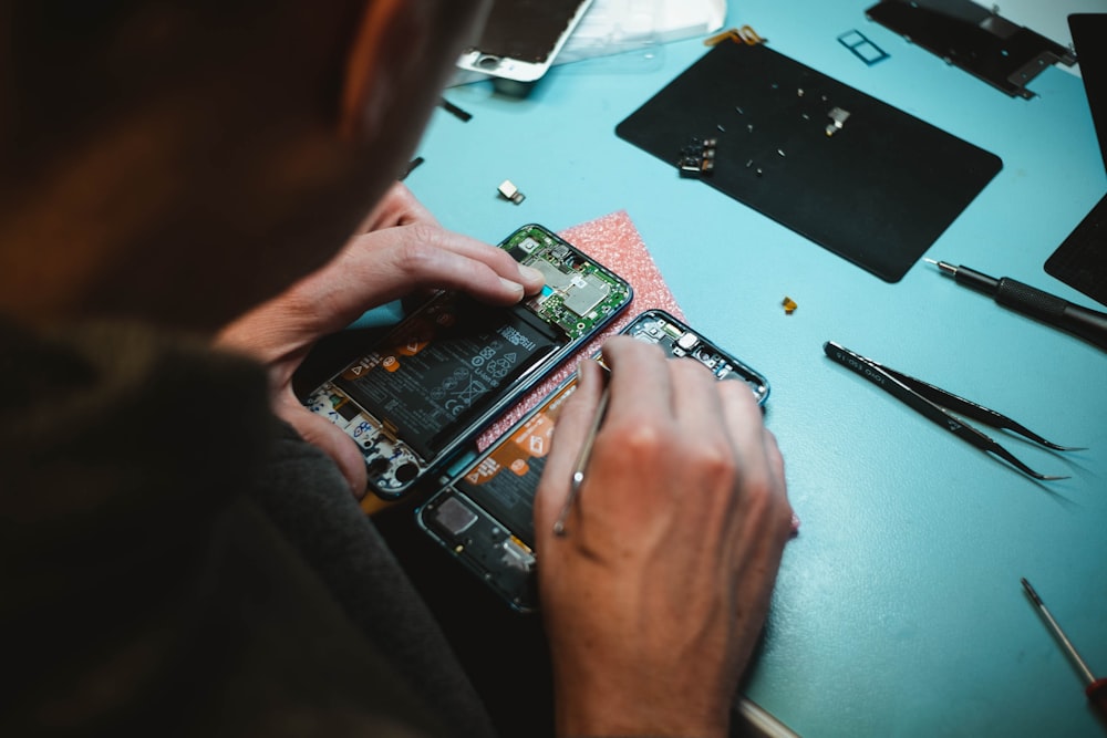 Persona reparando teléfonos inteligentes debajo de una mesa iluminada