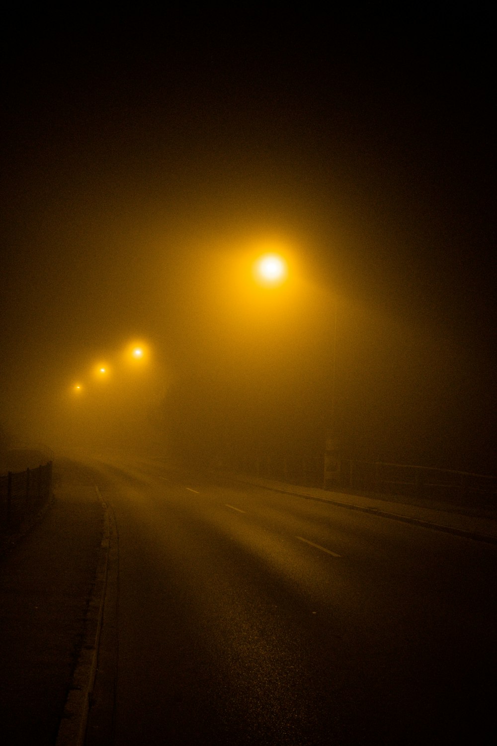 a foggy street with street lights on a foggy night