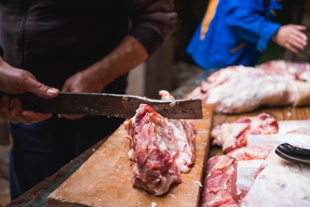 person chopping meat on board