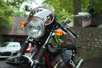 Close-up of a shiny motorbike parked beside a rustic wooden fence with mountains in the background
