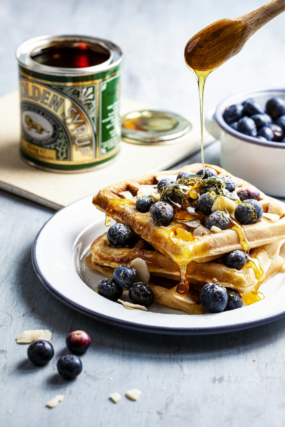 person putting honey on waffle with blueberry fruits