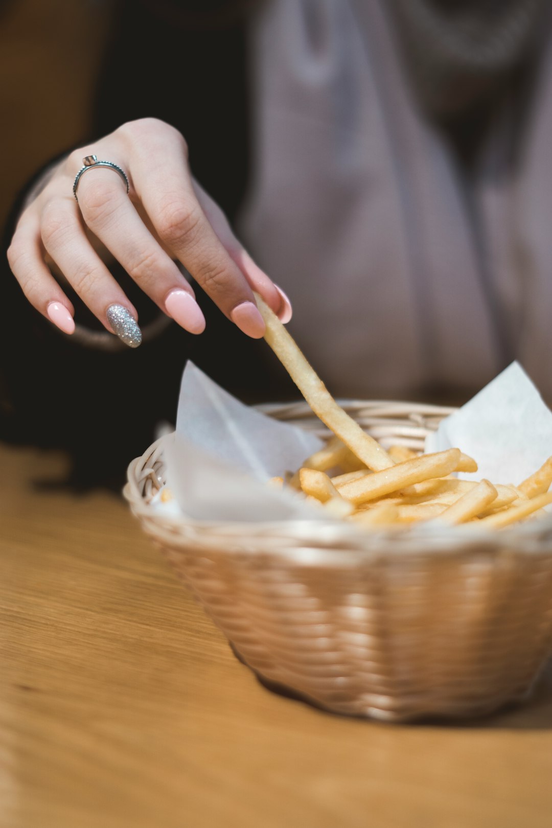 woman eating potato fries on wicker basket