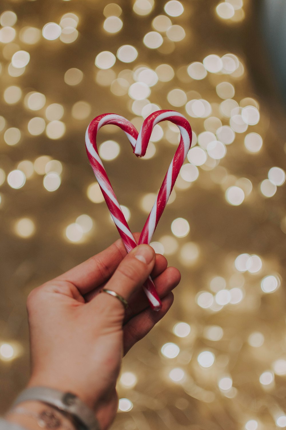 person holding candy cane shaped to a heart