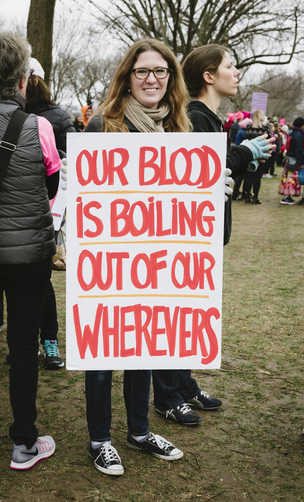 woman holding red and white our blood is boiling out of our wherevers sign