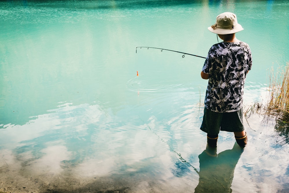 man wearing black shirt and shorts fishing on river