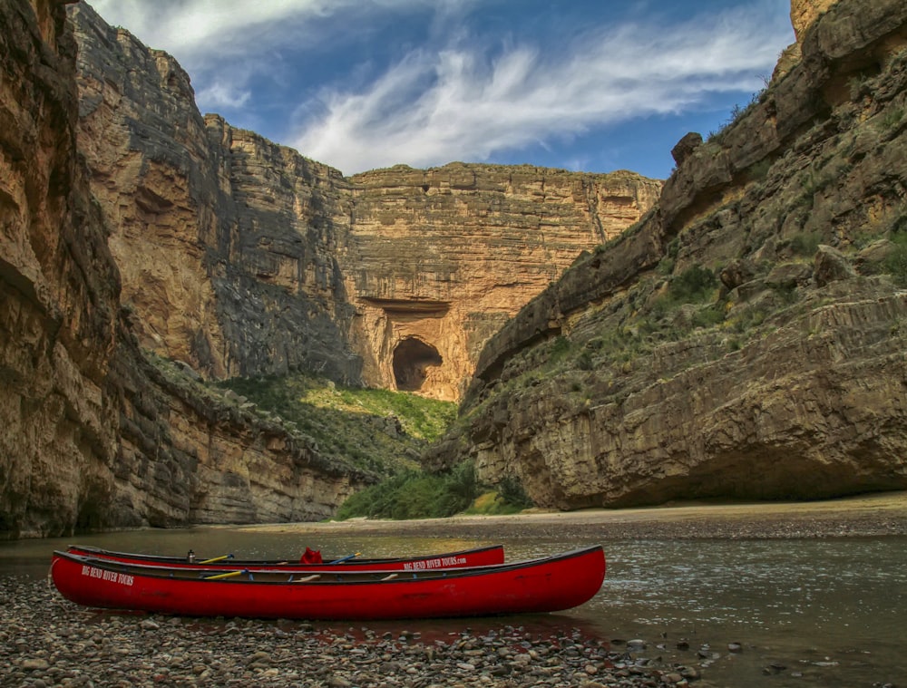 red canoe on soil with view of mountains during daytime