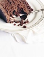 A slice of rich, layered cake with a fork resting on a pastel plate, ready to be enjoyed.