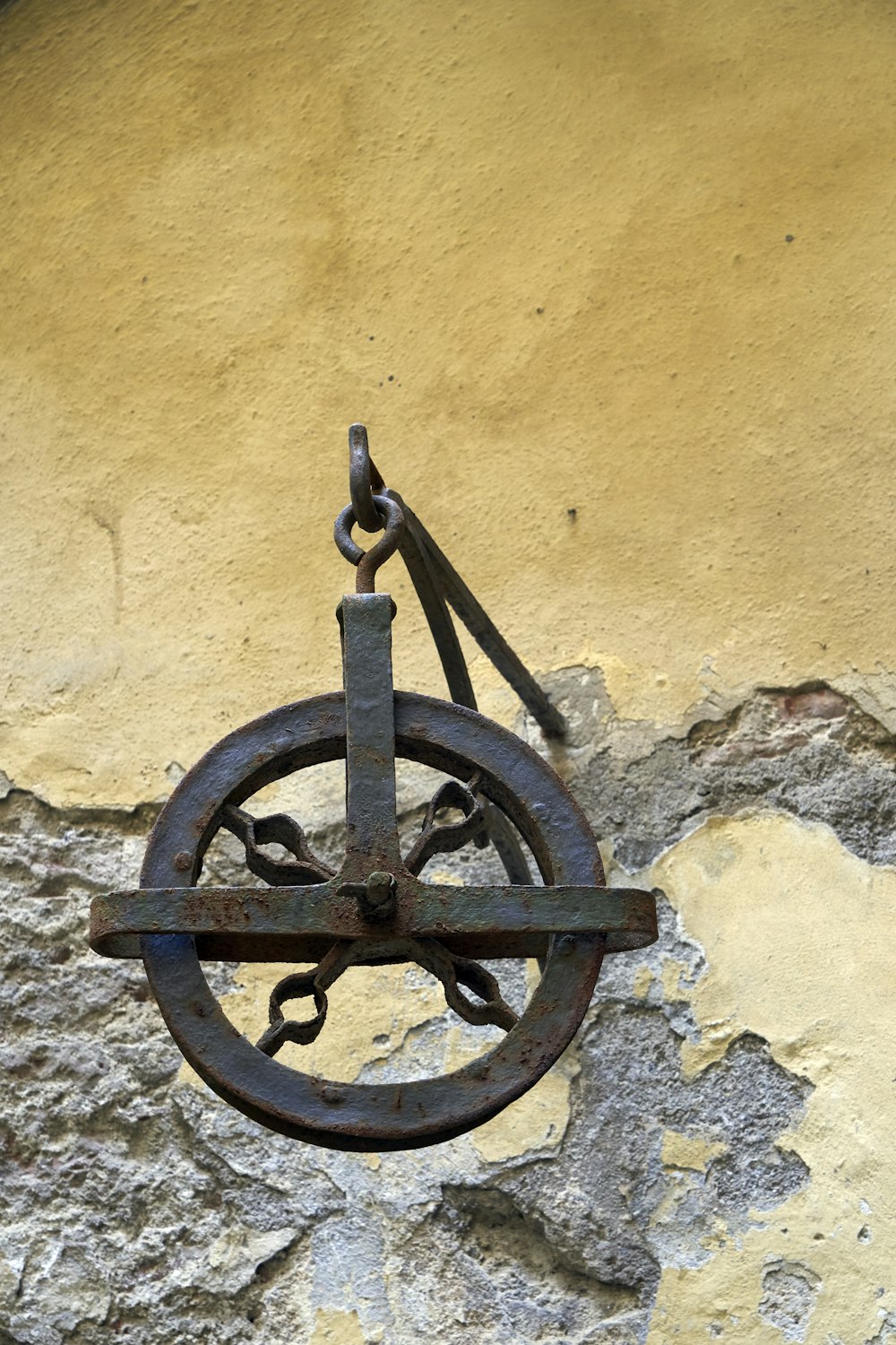 a rusty clock hanging on a yellow wall